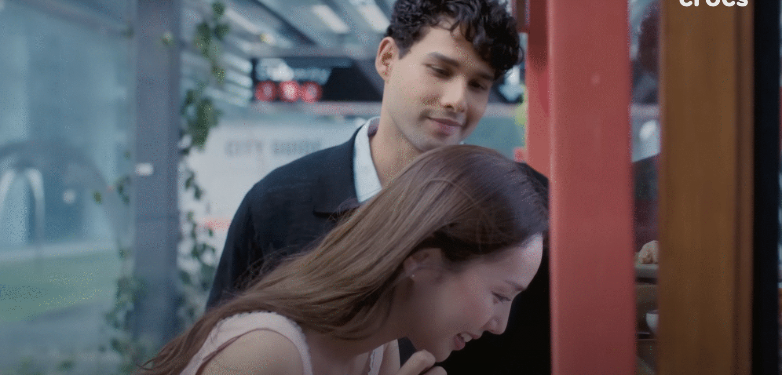 t: "Crocs monsoon advertisement featuring Bollywood actor Siddhant Chaturvedi and Korean actress Chae Soobin sharing a tender moment under an umbrella in the rain, with soft cinematography and K-drama inspired visual aesthetics